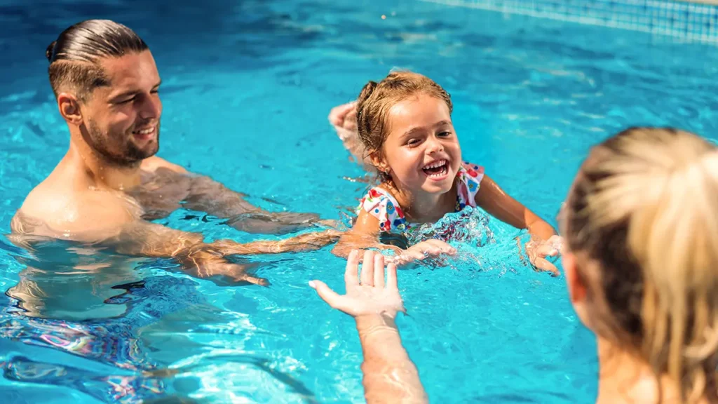 Un homme avec sa femme et sa fille nageant dans une piscine